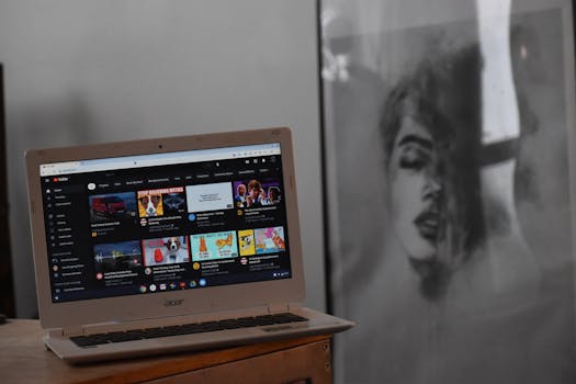 A cozy indoor setting with an Acer laptop displaying YouTube on a wooden table beside artwork.
