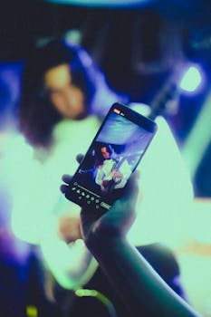Artwork of a rock guitarist captured on a smartphone during a concert.