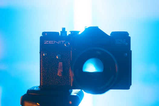 Close-up of Zenit EM camera in a dramatic blue-lit setting, showcasing its retro charm.